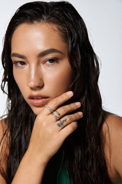 Genç bir kadın ıslak saçlarıyla zarafetini sergilerken zarif yüzükler sergiliyor..