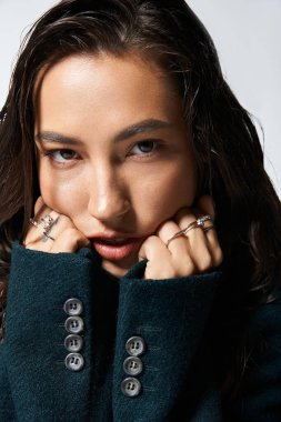 Şık bir kadın zarif bir şekilde kendine güvenen bir yüz ifadesiyle poz verir, sofistike stilini sergiler..