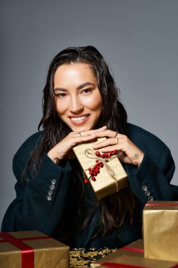 A sophisticated woman in stylish attire smiles playfully while surrounded by festive gifts. clipart