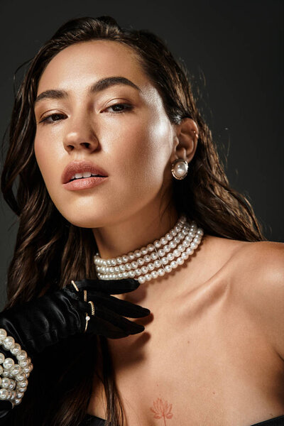 Молодая женщина излучает изысканность в элегантной одежде, подчеркнутой потрясающими жемчужными украшениями.