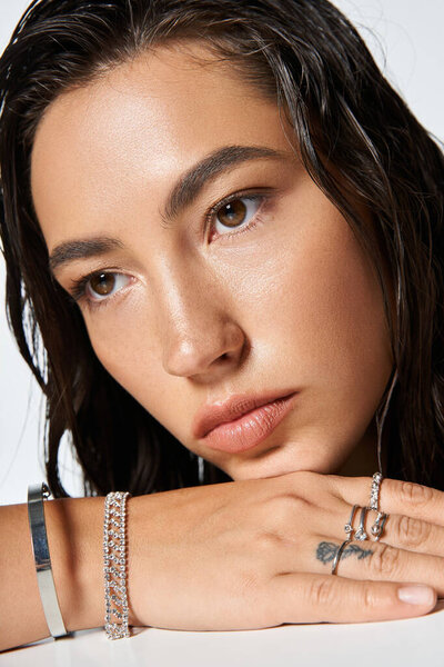 Изысканная женщина в элегантной одежде нежно позирует, демонстрируя потрясающие украшения.