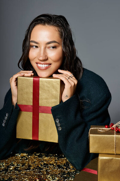 An elegant woman beams, holding a shiny gift and radiating holiday joy.