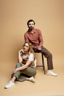 A middle aged couple showcases their fashion sense while striking poses in a cozy studio. clipart