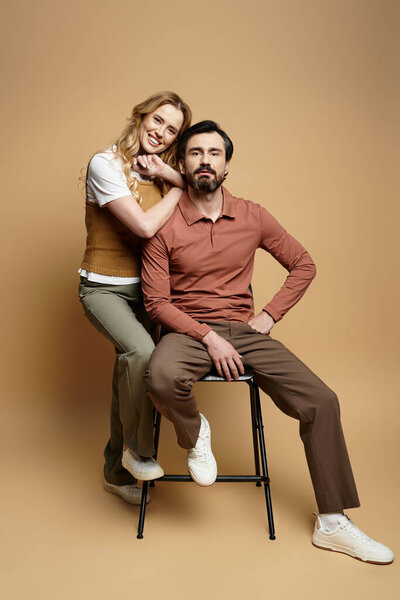 A joyful middle aged couple is playfully posing in a modern studio with a warm backdrop.