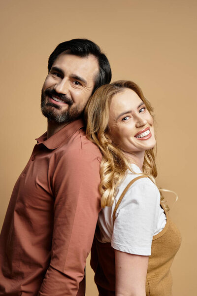 Веселая пара позирует спиной к спине с улыбками, наслаждаясь компанией друг друга.