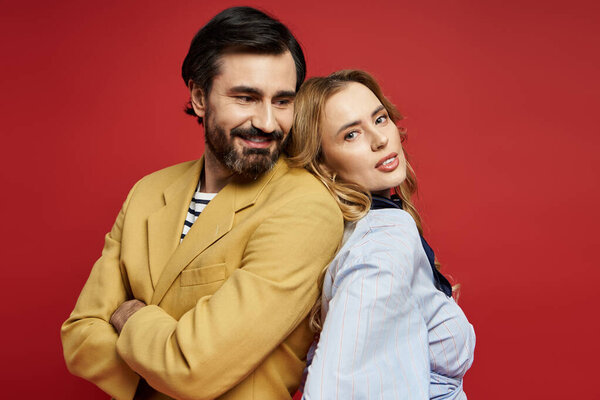 Веселая пара средних лет демонстрирует свою живую личность, позируя спиной к спине..