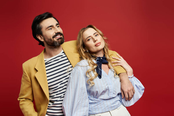 Стильная пара игриво позирует в яркой красной обстановке, источая очарование и уверенность.