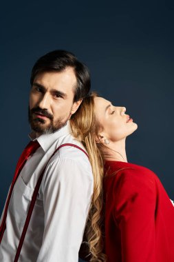 Orta yaşlı bir çift sırt sırta durup şık kıyafetlerini ve özgüvenlerini sergiliyor..