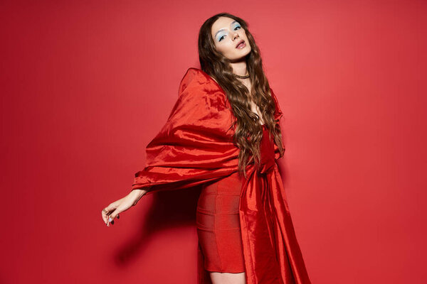 Женщина демонстрирует свое потрясающее чувство стиля с текущей красной одеждой, позируя уверенно.
