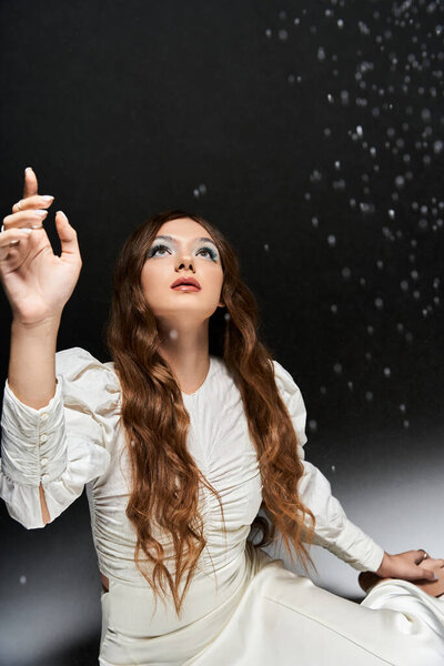 Красивая молодая женщина с длинными волосами смотрит вверх, очарованная сверкающей пылью в темноте.