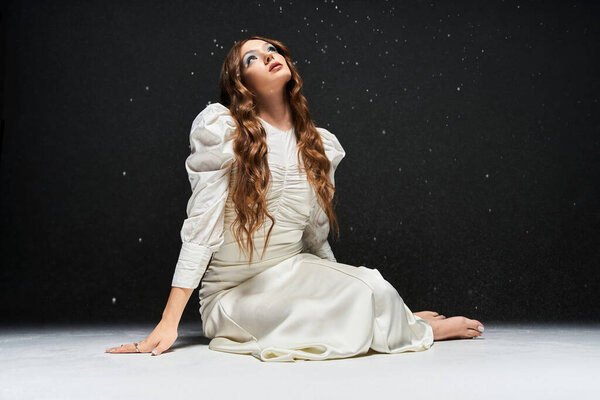 Ошеломляющая молодая женщина смотрит вверх, ее длинные волосы каскадом вокруг нее, в окружении блесток.