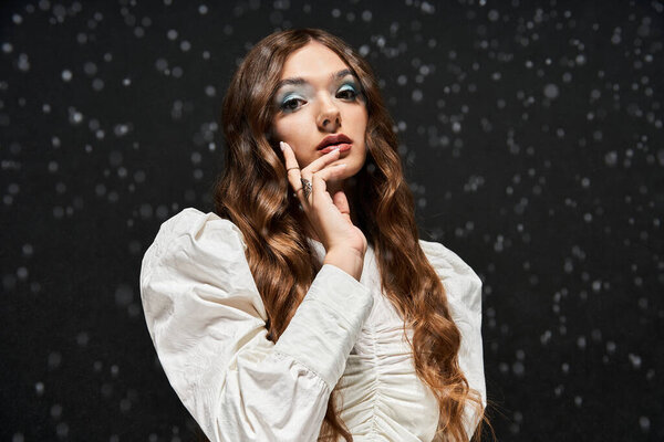 Молодая женщина в элегантной одежде изящно позирует, демонстрируя свой талант среди снежинок.