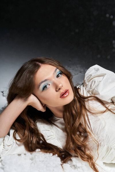 Красивая молодая женщина с длинными волосами изящно расслабляется среди мягкого снега.