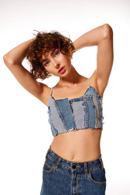 A young woman confidently poses in a unique denim outfit against a simple backdrop. clipart