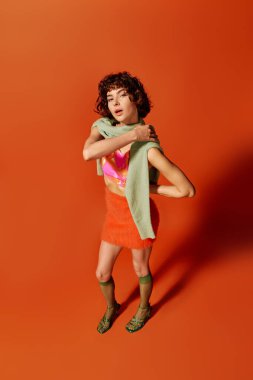 A young woman showcases her style and emotion while posing against a bold orange backdrop. clipart