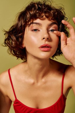 Kıvırcık saçlı genç bir kadın izleyiciye bakıyor, özgüven ve duygu saçıyor..