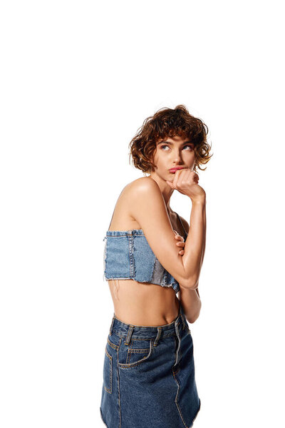 Молодая женщина выражает глубокие эмоции в стильной джинсовой одежде.