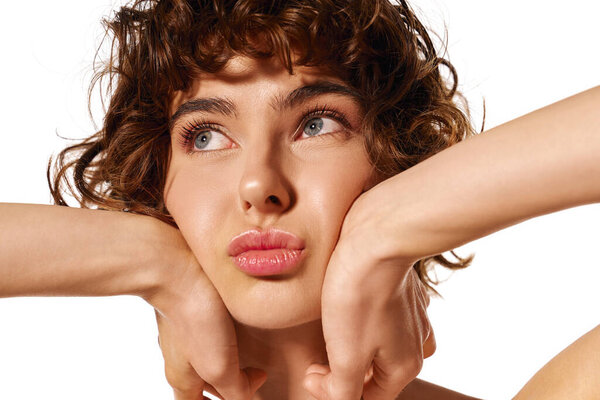 Молодая женщина вдумчиво смотрит вверх, опираясь подбородком на руки, передавая эмоции..