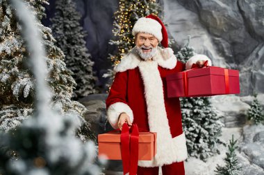 Neşeli bir Noel Baba sihirli karlı bir arazide dururken iki renkli hediye alır..