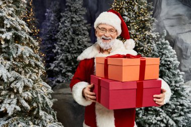 Neşeli bir Noel Baba, karlı ağaçlara sarılı hediyeler tutar..