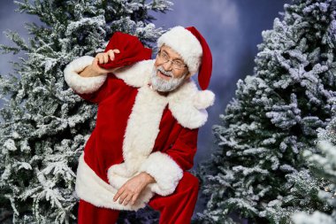 Neşeli bir Noel Baba, karlı bir ormanda eğleniyor, neşeli bir neşe saçıyor..