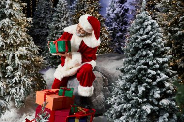 Santa Claus surrounded by snowy trees, thoughtfully examining colorful gifts for Christmas. clipart