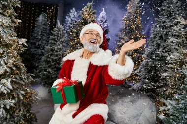 Noel Baba, ışıldayan ışıklar ve karlı ağaçlarla çevriliyken tatil neşesini paylaşıyor..
