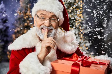 Noel Baba mutlu bir anı paylaşıyor, karlar ve parıldayan tatil ışıklarıyla çevrili..