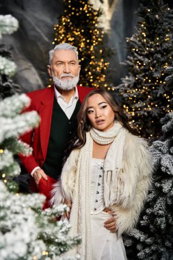 Ilık giyinmiş iki kişi, parıldayan ışıklarla çevrili sıcak bir Noel atmosferinin tadını çıkarıyor..