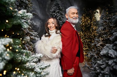 Noel 'i birlikte kutluyoruz. Parlak süslemeler ve karlı ağaçlar arasında bir çift duruyor..