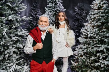 Neşeli yaşlı bir adam ve genç bir kadın. Karlı bir orman arka planında Noel modasını somutlaştırıyorlar..