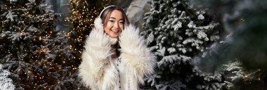 Genç bir kadın, güzel karlı ağaçlar ve ışıklarla çevrili Noel ruhunun tadını çıkarıyor..
