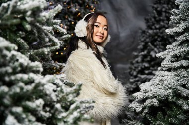 Surrounded by snow covered trees, a woman radiates joy in her festive winter attire. clipart