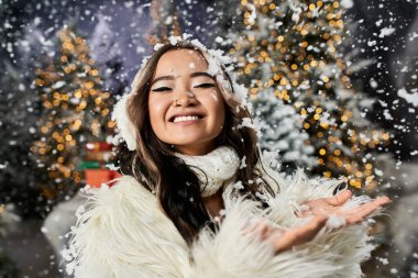 Neşeli bir birey, Noel 'in sihrini kar yağışı ve parıldayan ışıklarla kucaklıyor..