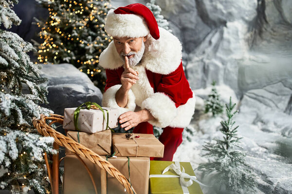 Веселая фигура, одетая как Санта Клаус тихо устраивает подарки на снежном фоне.