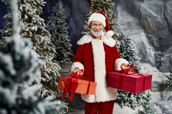 Веселый Санта держит два обернутых подарка в снежном пейзаже.