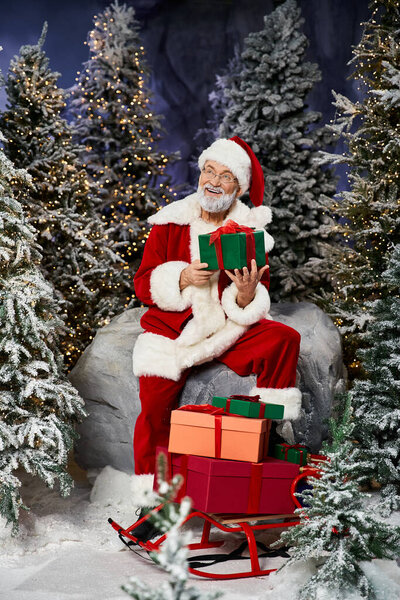 A cheerful figure in a red suit joyfully presents colorful presents amidst snowy trees.