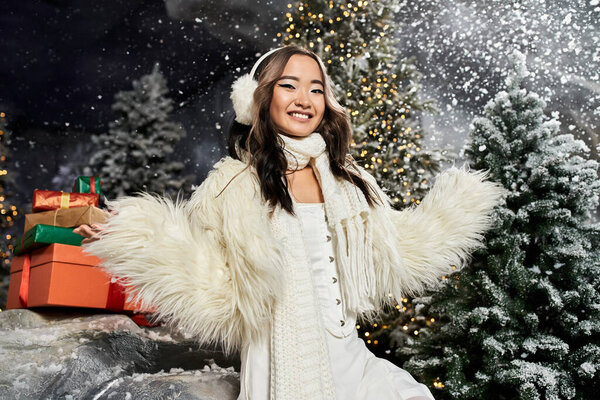 Веселый молодой человек наслаждается праздничным духом Рождества в окружении снега и праздничных подарков.