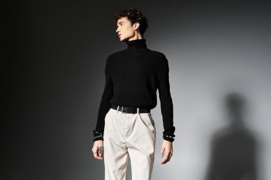 Kıvırcık saçlı şık bir genç adam koyu gri bir arka plana karşı gösterişli bir kıyafete güvenir..