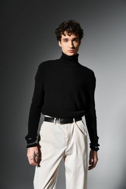 Yakışıklı genç bir adam, siyah balıkçı yaka ile karizmatik tarzını sergiliyor, koyu bir arka planda kendine güveni var..