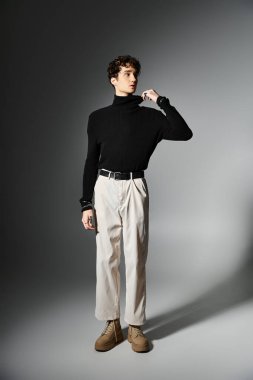 Yakışıklı genç bir adam, koyu gri bir zemin üzerinde kıvırcık saçlı, parlak bir görünüm sergiliyor..