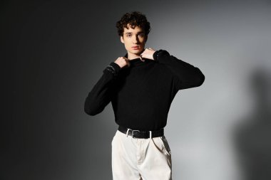 Şık bir genç adam, koyu gri arka planda kendine has duruşu olan şık kıyafetini sergiliyor..