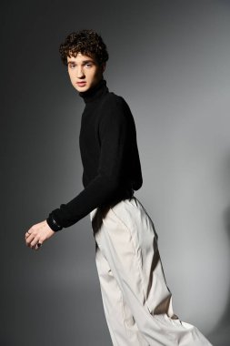 Şık bir genç adam koyu gri bir arka planda kendine güvenerek poz veriyor, zarafet ve moda sergiliyor..