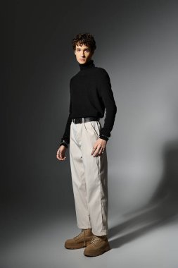 Çekici bir genç adam şık siluetini sergiliyor ve kendine güvenerek şık bir şekilde poz veriyor..