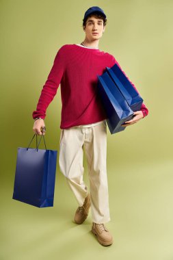 Kıvırcık saçlı şık bir genç adam alışveriş torbaları taşıyor ve Kara Cuma satışlarının heyecanını yaşıyor..