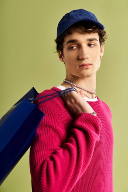 Yakışıklı genç bir adam Kara Cuma 'da alışveriş çantalarını tutuyor ve moda tarzını bir stüdyo arka planında sergiliyor..