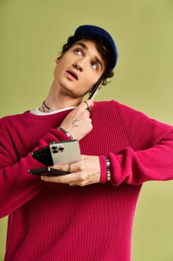 Pembe kazak giyen yakışıklı genç bir adam elinde telefon tutarken neşeli bir an yaşıyor..