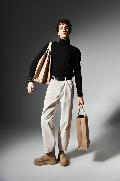 Модный молодой человек держит сумки для покупок, демонстрирует свои кудрявые волосы и модный наряд во время событий Черной пятницы.