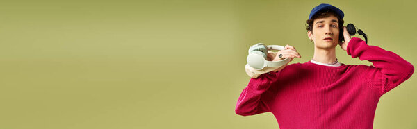 Веселый молодой человек демонстрирует свой стиль в розовом свитере, уверенно позируя на ярком фоне.