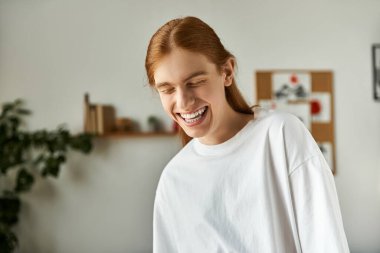 A young man with long hair smiles widely, embodying happiness while enjoying friendly company. clipart